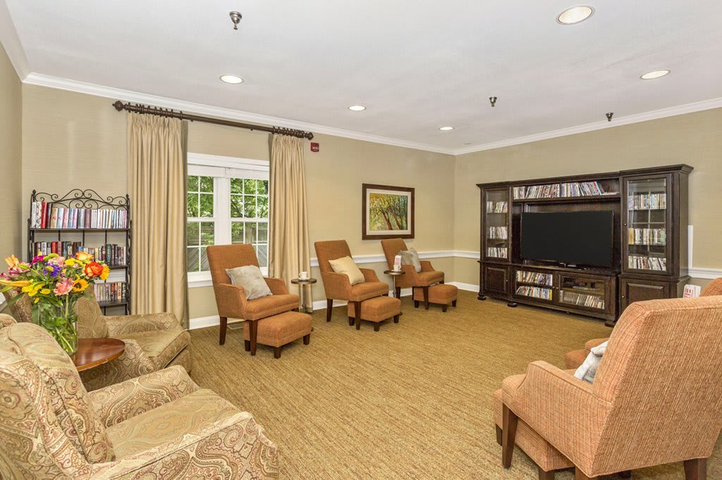 A cozy living room with comfortable seating, a large television, and a warm carpeted floor.