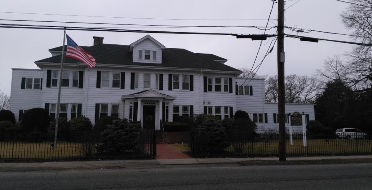 A large residential house with a white exterior and dark shutters.