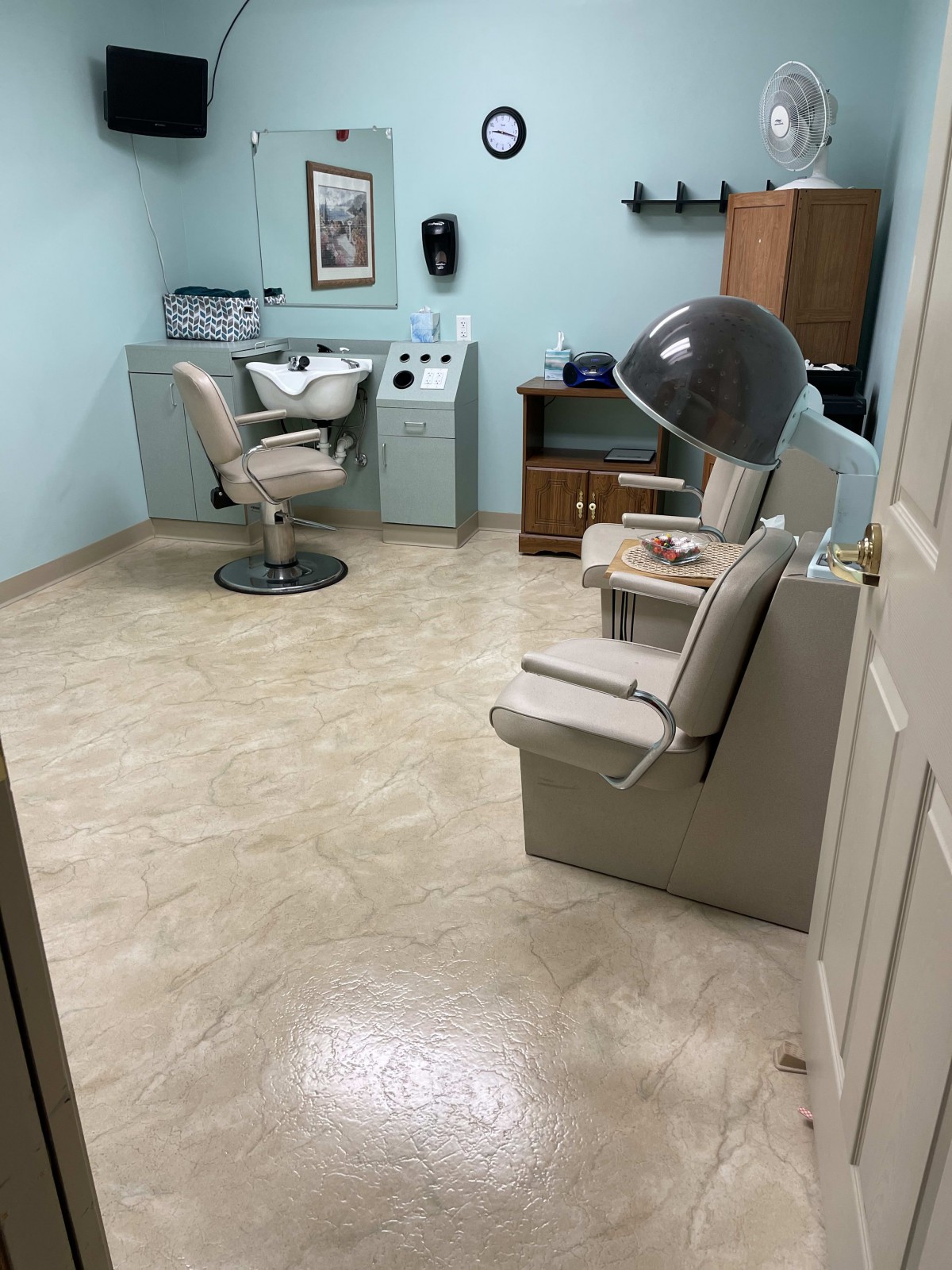 A cozy salon room with a hair drying station and comfortable chairs.