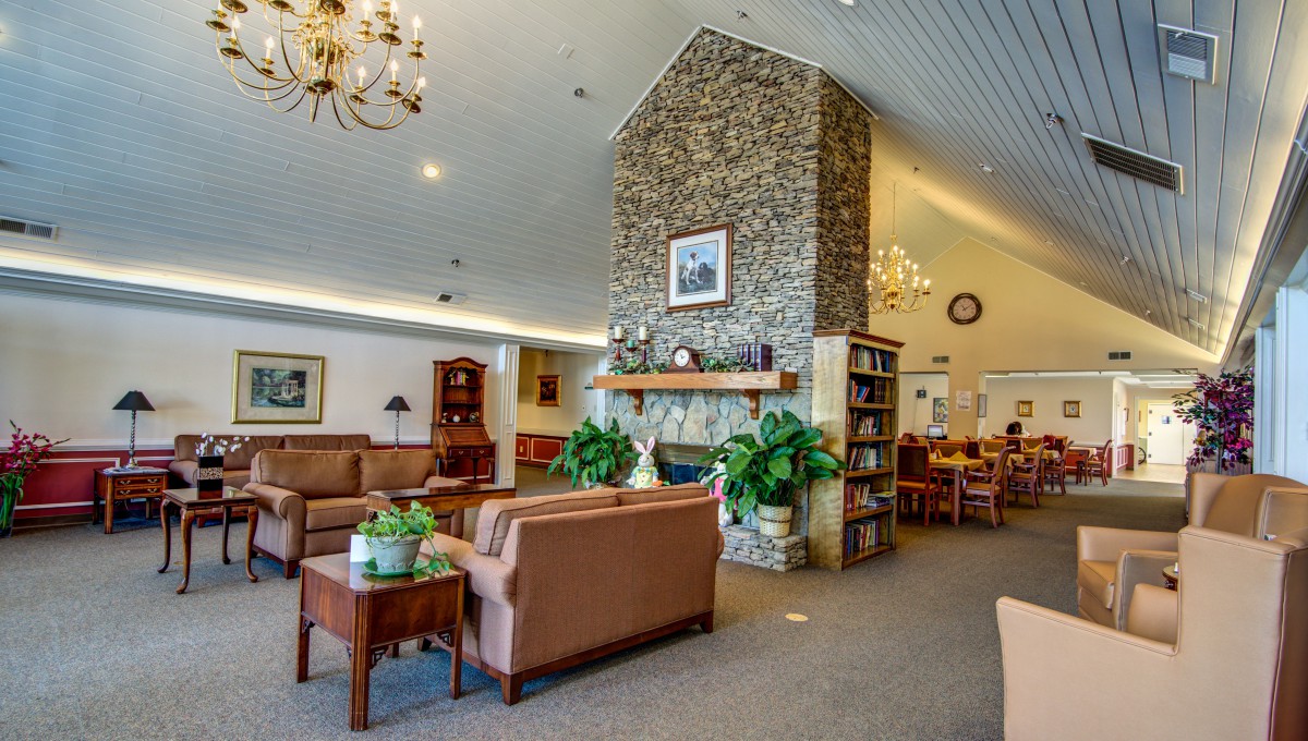 A cozy lounge area featuring a stone fireplace, comfortable seating, and elegant chandeliers.