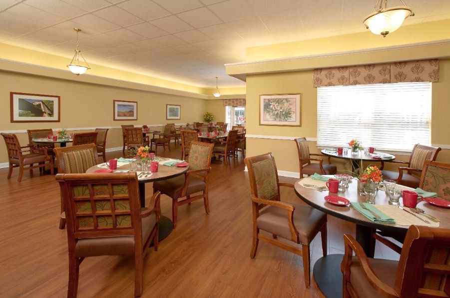 An empty dining room with neatly arranged tables and chairs, featuring warm lighting and tasteful decor.