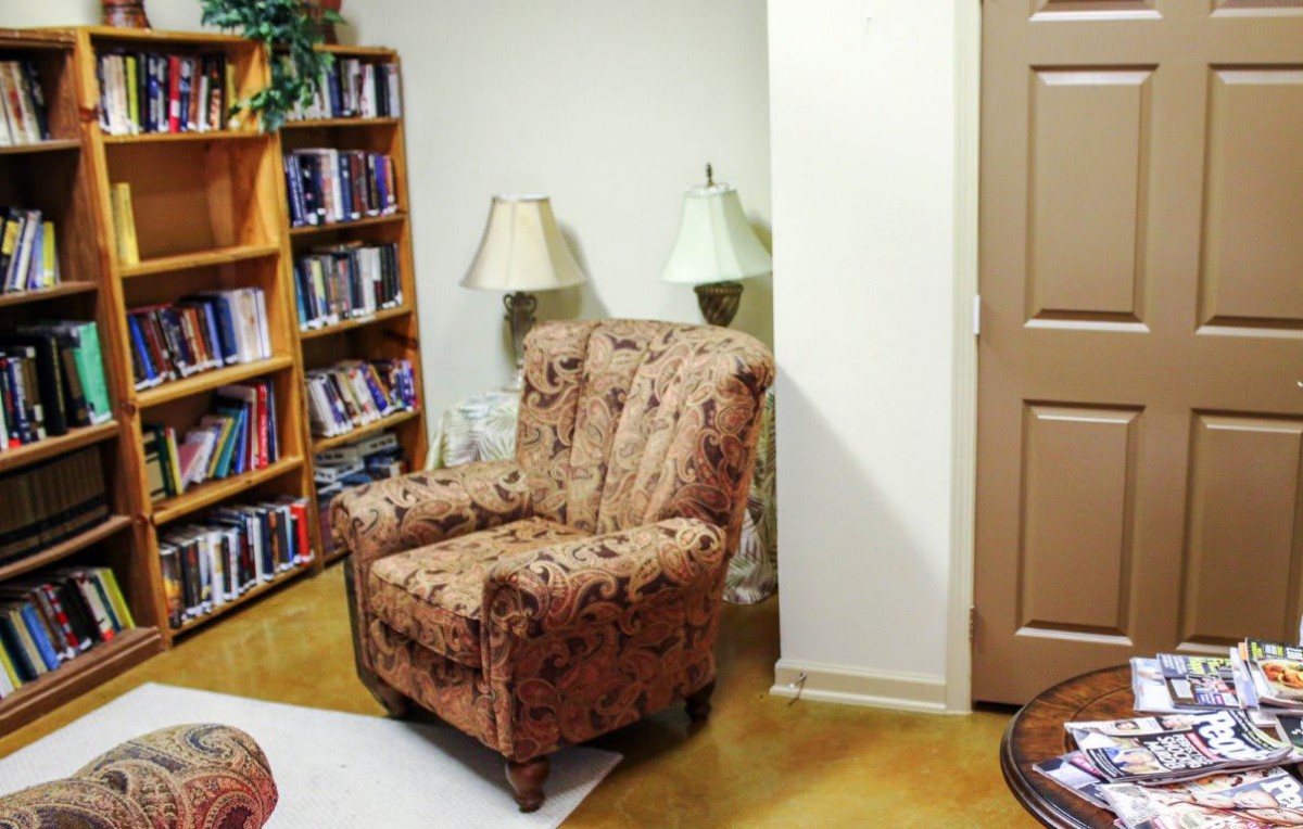 A cozy reading corner with an armchair and a bookshelf filled with books.