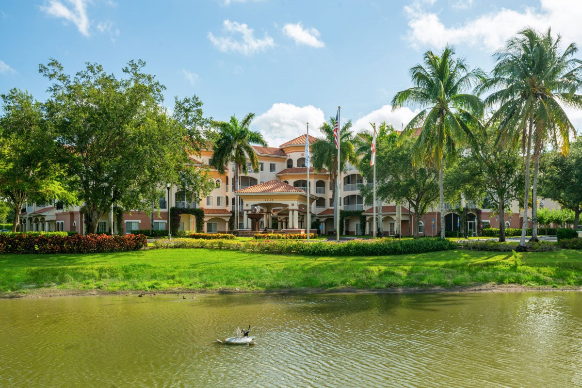 A scenic view of a resort building surrounded by palm trees and a tranquil lake.