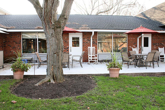 A backyard with a patio area featuring outdoor seating and potted plants, set against the backdrop of a house.