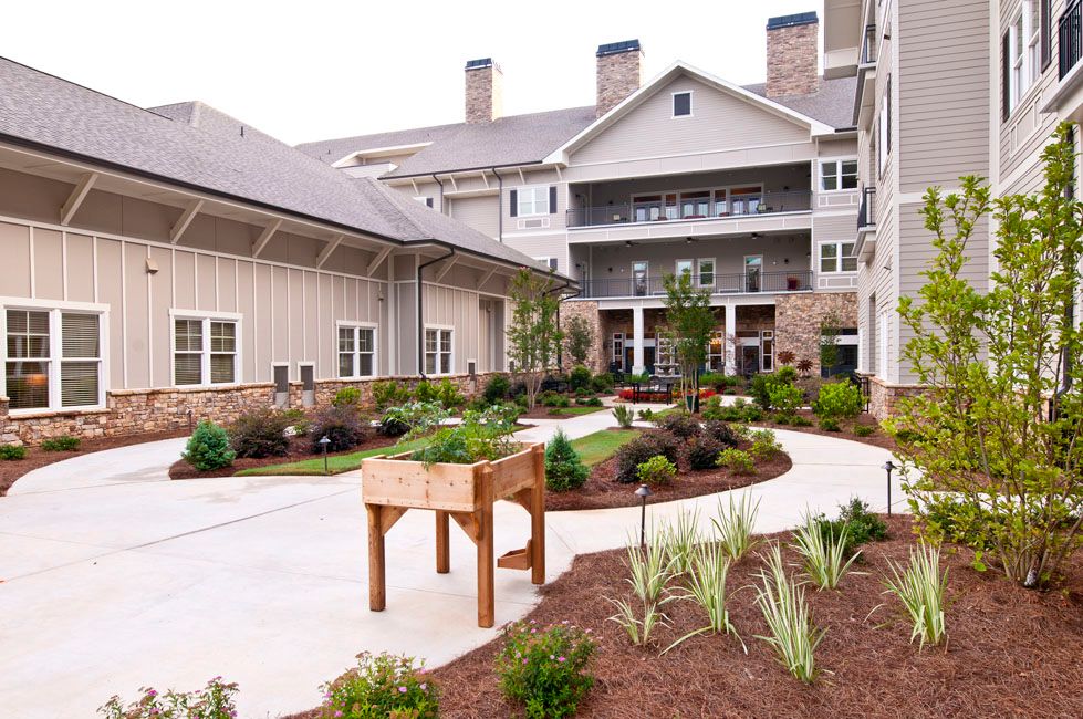 A beautifully landscaped courtyard with a garden and pathways in front of a residential building.
