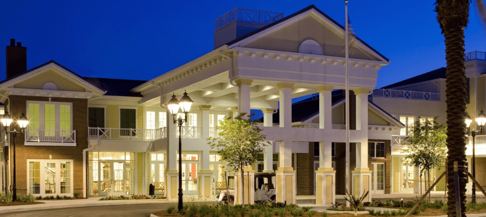A well-lit building entrance with columns and a porch at night.