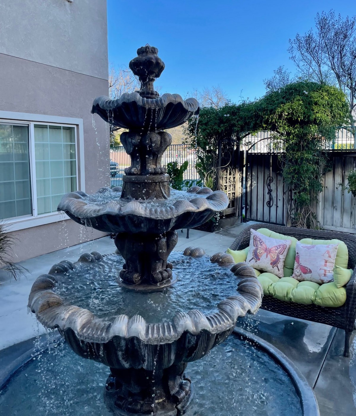 A serene outdoor patio with a decorative fountain and comfortable seating area.