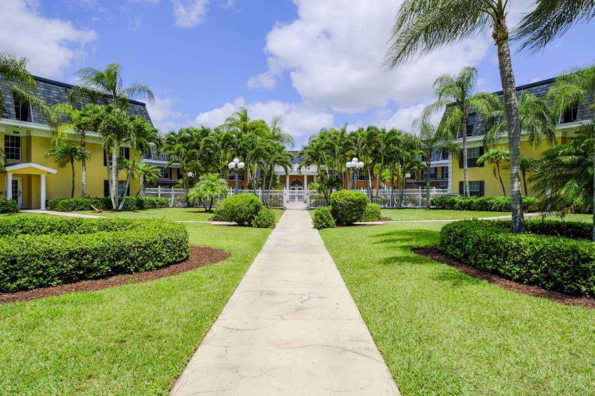 A beautiful tropical resort with lush gardens and palm trees under a clear blue sky.