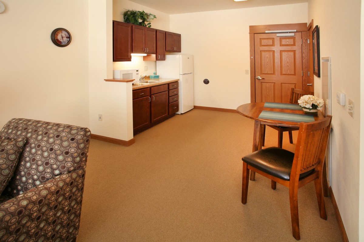 A cozy apartment interior featuring a kitchenette and dining area with wooden cabinets.