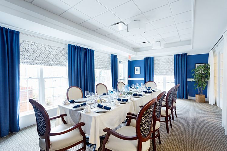 A formal dining room with blue curtains and a neatly set table.