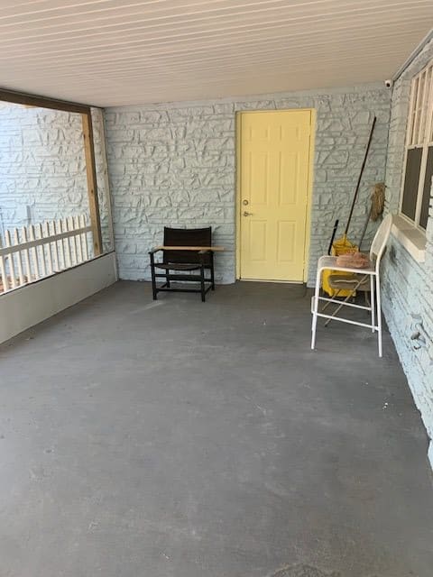 A simple porch with a chair, small table, and yellow door.