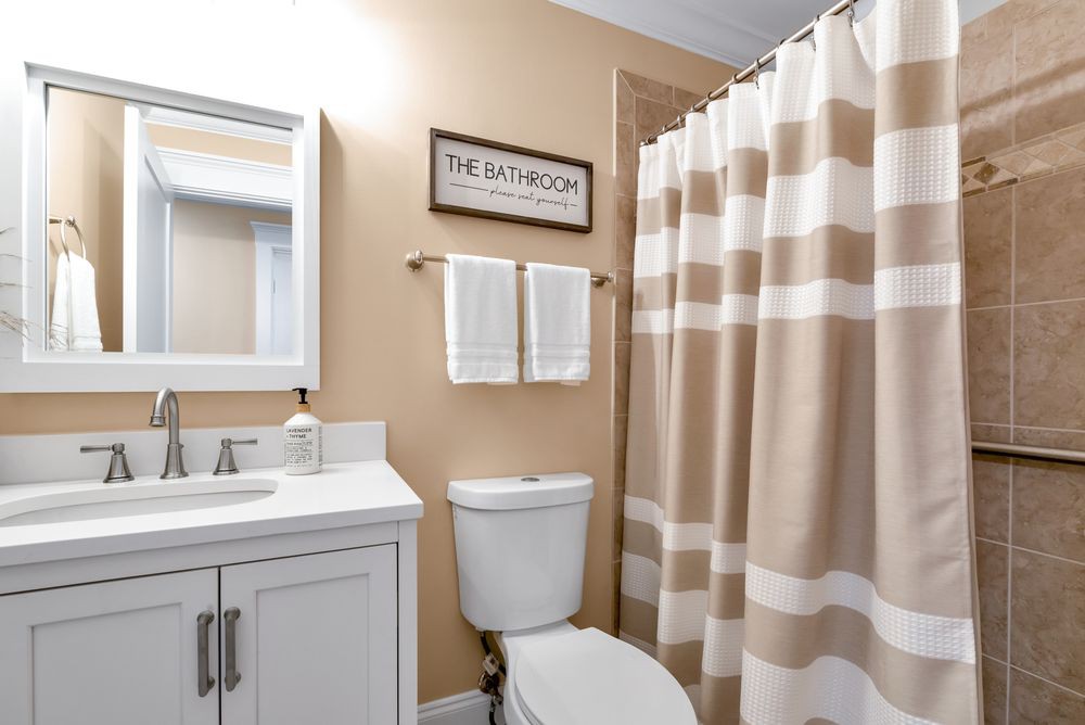 A neatly organized bathroom with a striped shower curtain and a vanity with a mirror.