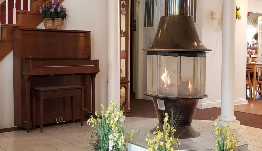 A cozy interior featuring a modern fireplace, a piano, and decorative floral arrangements.