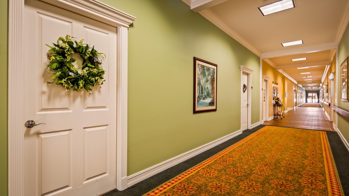 A hallway with green walls, decorated doors, and framed artwork.