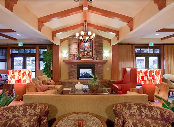 A cozy living room with a warm fireplace, comfortable seating, and elegant wood beam ceiling.