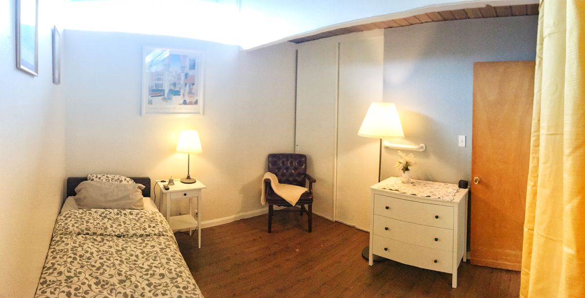 A cozy bedroom with a bed, two lamps, a chair, and a dresser.