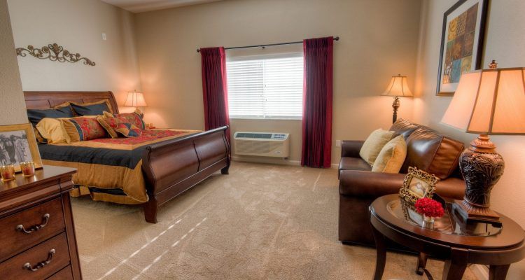 A cozy bedroom with a large bed, sofa, and soft lighting.