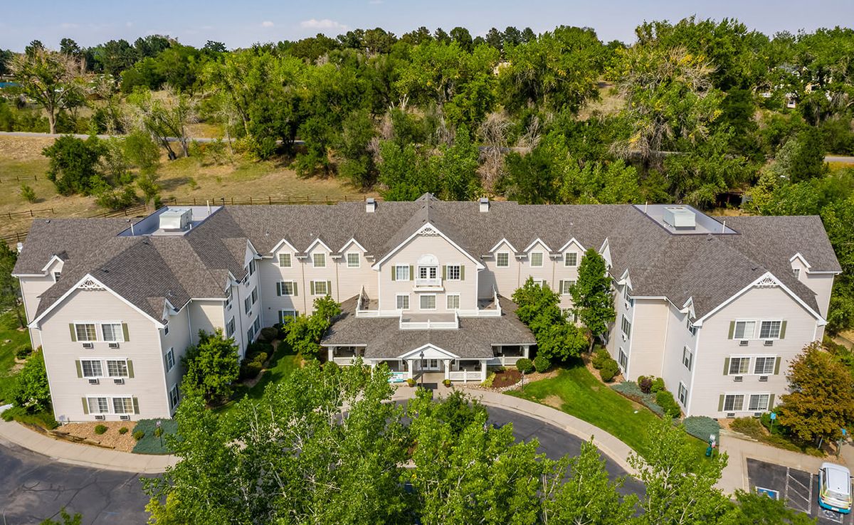 Aerial view of a large mansion surrounded by lush greenery and a landscaped driveway.