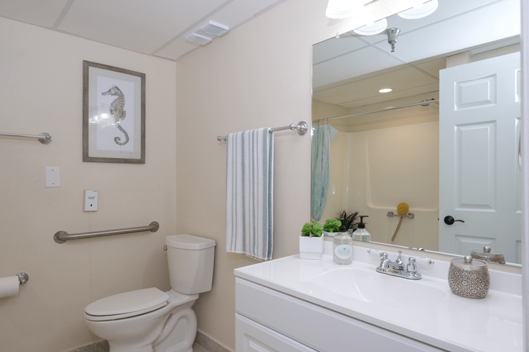 A clean and well-lit bathroom with a toilet, sink, and mirror.
