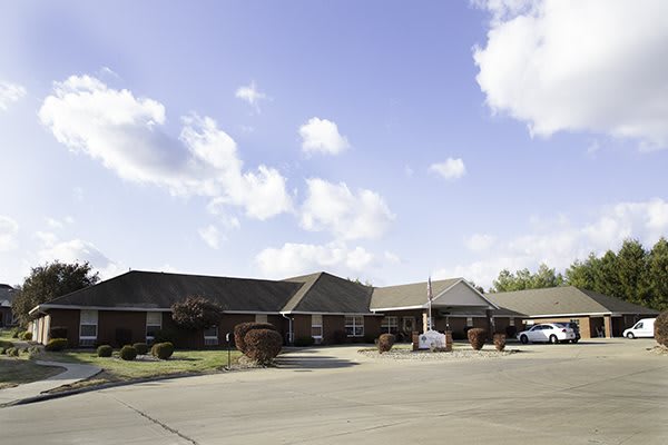 A residential building with a driveway under a partly cloudy sky.