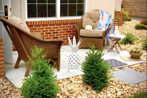 A cozy outdoor patio setup featuring lounge chairs, decorative plants, and a playful pineapple accent.