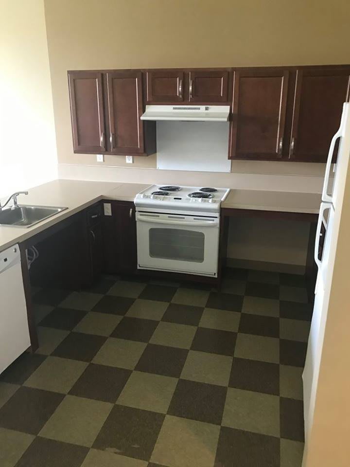 A clean, modern kitchen with dark wood cabinets, an oven, and tiled flooring.