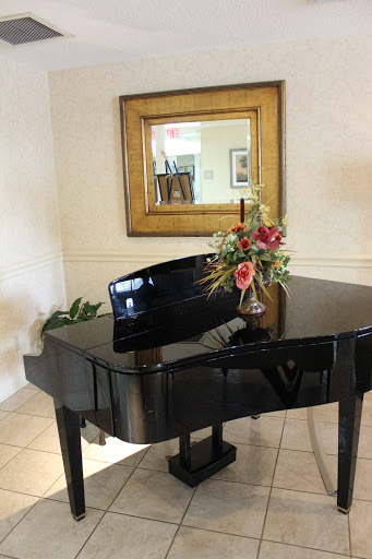 A stylish grand piano accompanied by a beautiful floral arrangement and a decorative mirror.