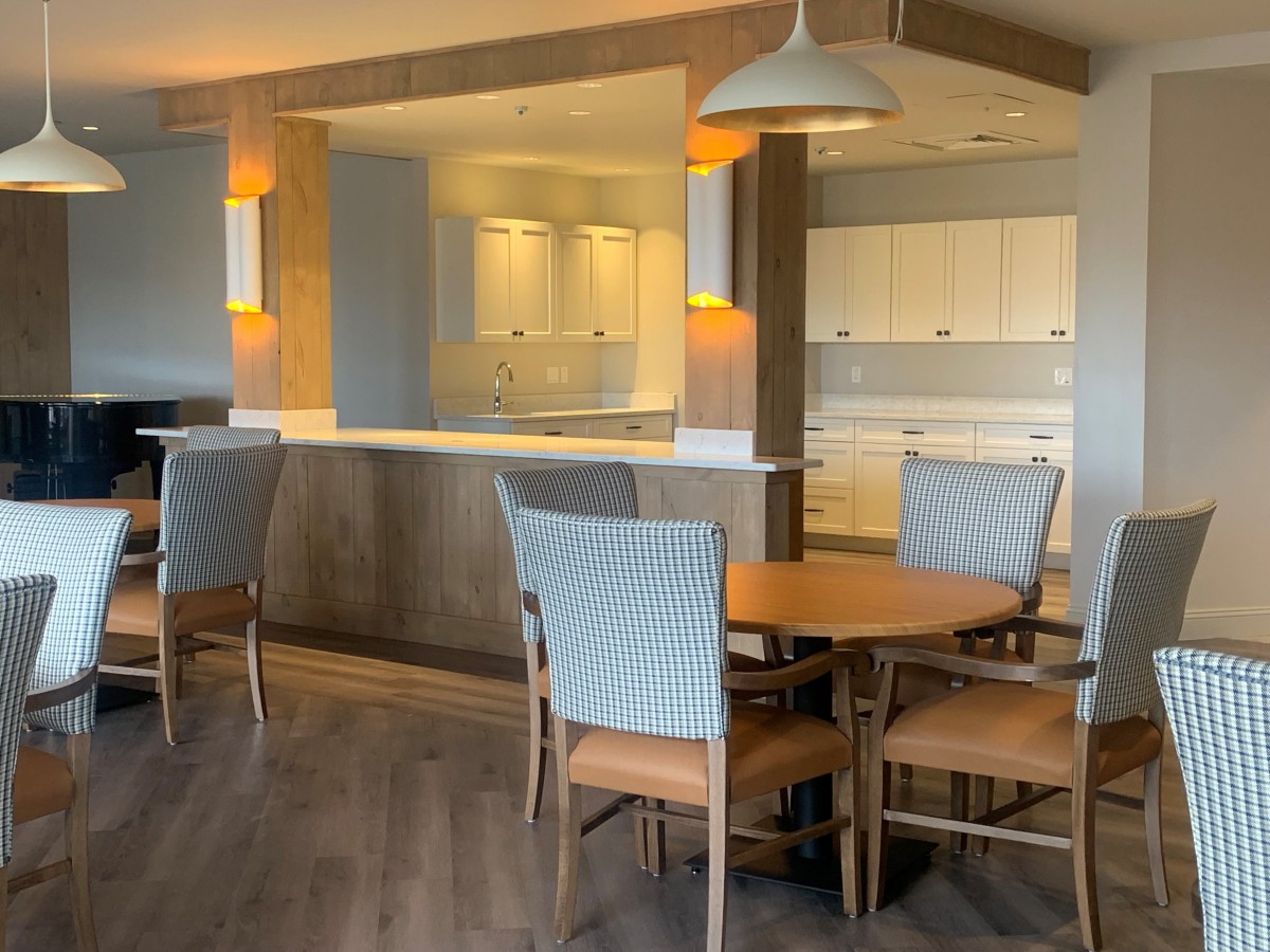 A modern kitchen and dining area with wooden furniture and pendant lighting.