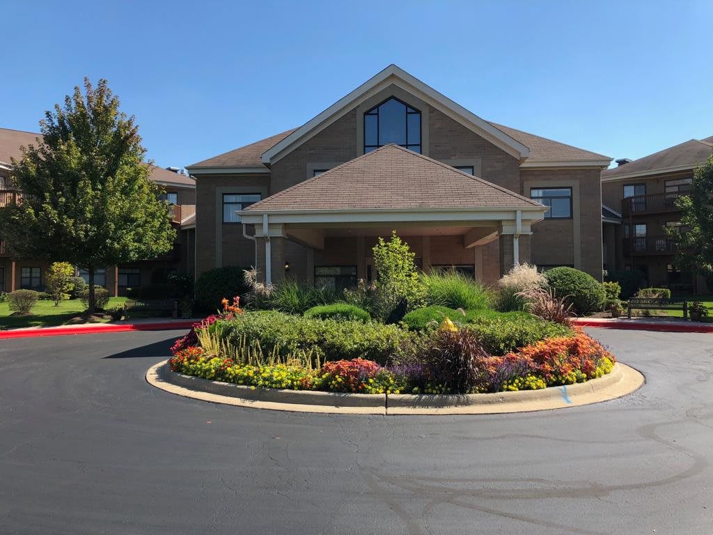 A well-maintained building with landscaped gardens and a circular driveway at the entrance.