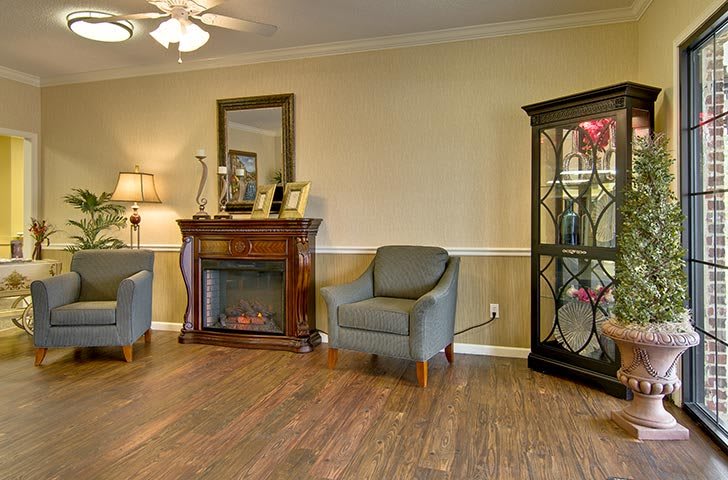 A cozy living room featuring a fireplace, armchair, and elegant display cabinet.
