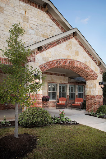 A beautifully designed house featuring a brick and stone exterior, complemented by a welcoming porch and garden.