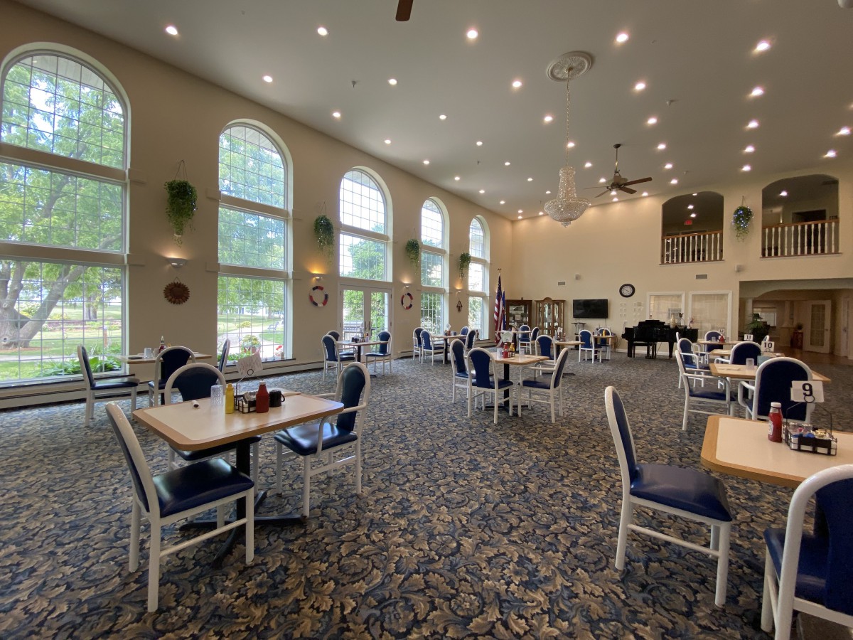 A spacious dining area with large windows and neatly arranged tables and chairs.