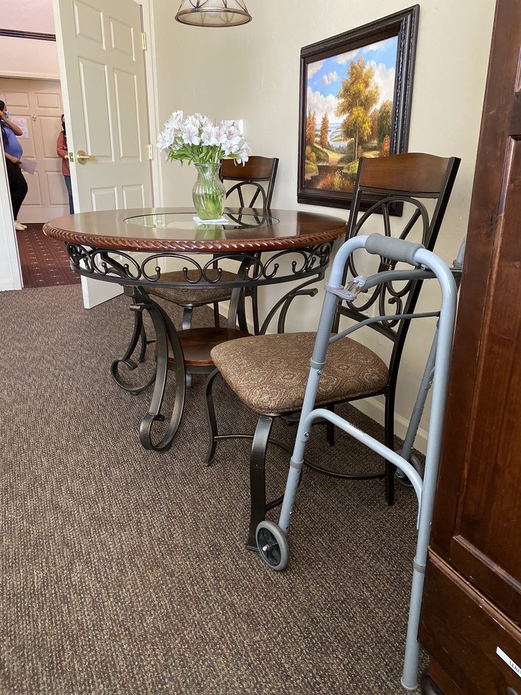 A cozy interior featuring a dining table set with flowers and a walker nearby.