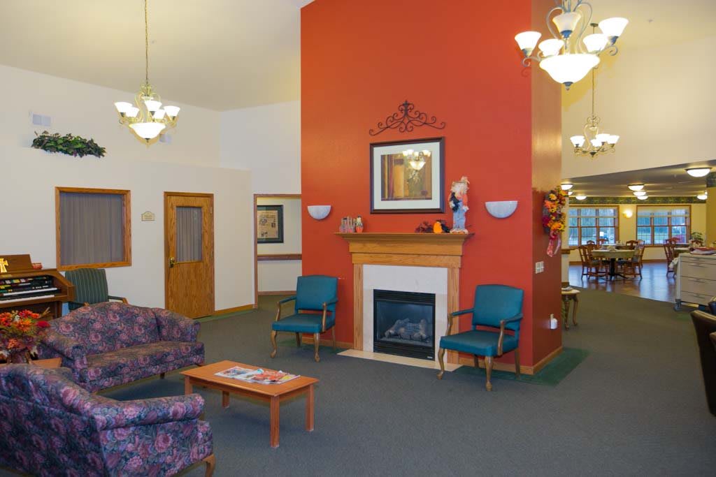 A cozy lobby area featuring a central fireplace, comfortable seating, and elegant chandeliers.