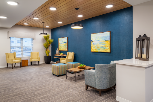 A modern lounge area featuring blue walls, comfortable seating, and vibrant artwork.