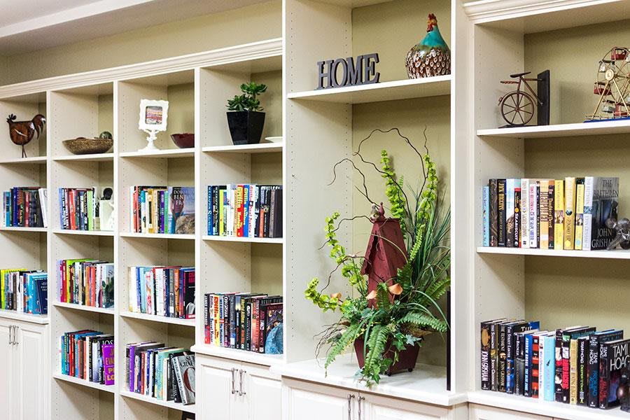 A neatly arranged bookshelf with books, decorative items, and indoor plants.