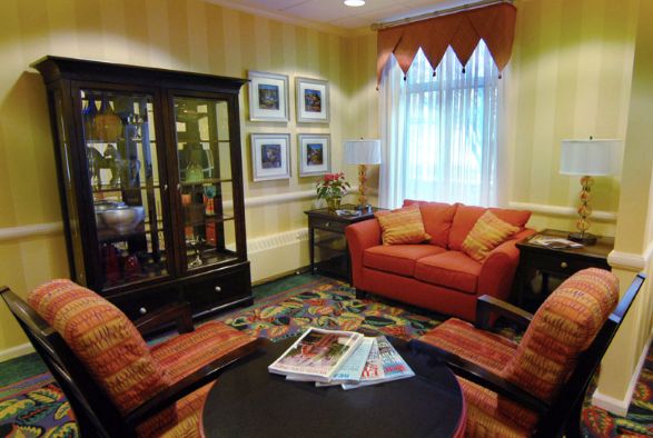 A cozy living room with a red sofa, matching armchairs, and a black cabinet displaying decorative items.