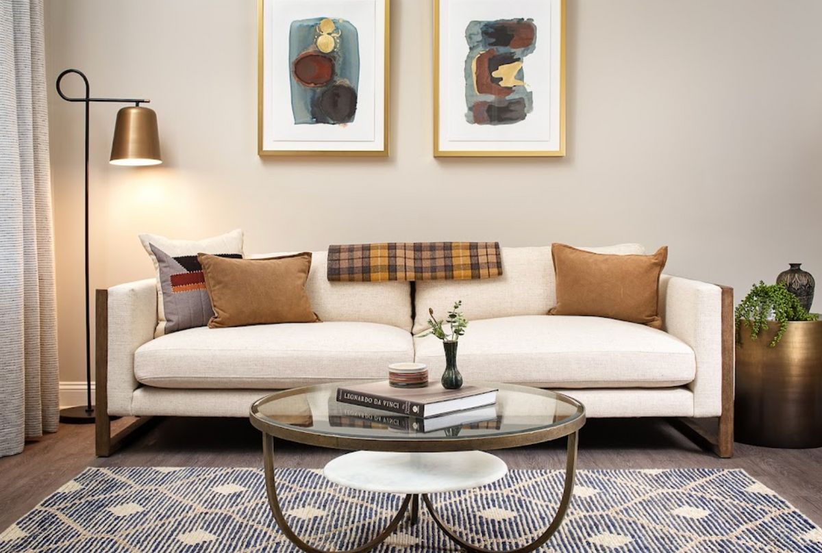 A modern living room with a stylish sofa, abstract artwork, and a decorative coffee table.