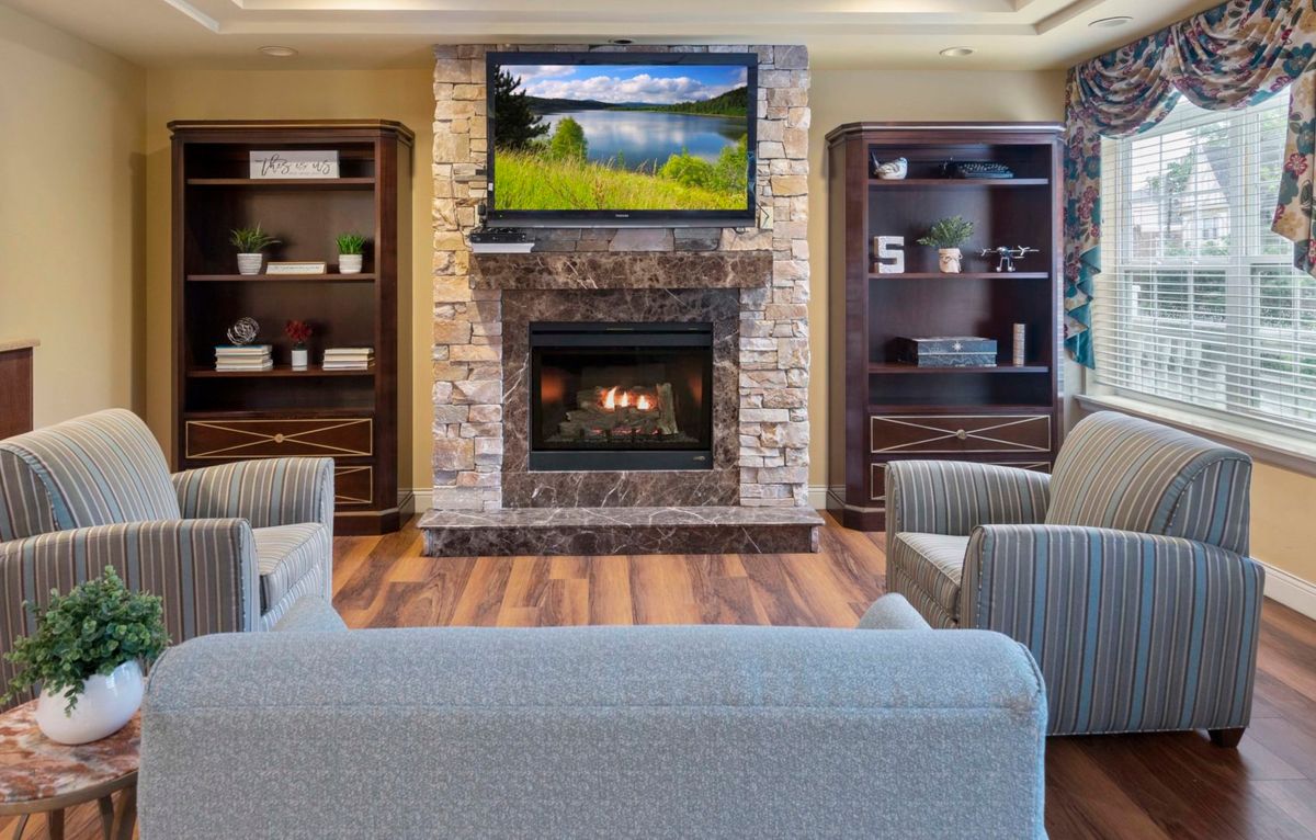 A modern living room featuring a central fireplace with a television mounted above, surrounded by elegant shelving and comfortable seating.
