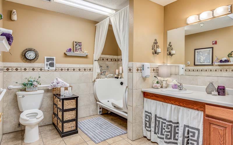 A cozy bathroom featuring a walk-in tub with curtains, a sink with a large mirror, and decorative elements.
