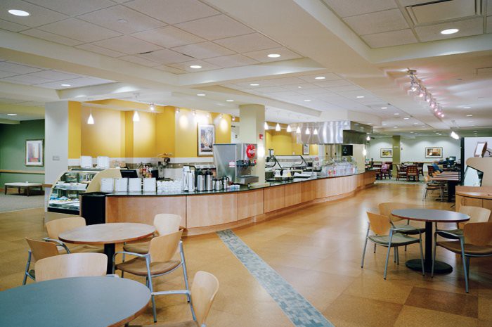 A spacious and modern cafeteria with tables, chairs, and a food service counter.