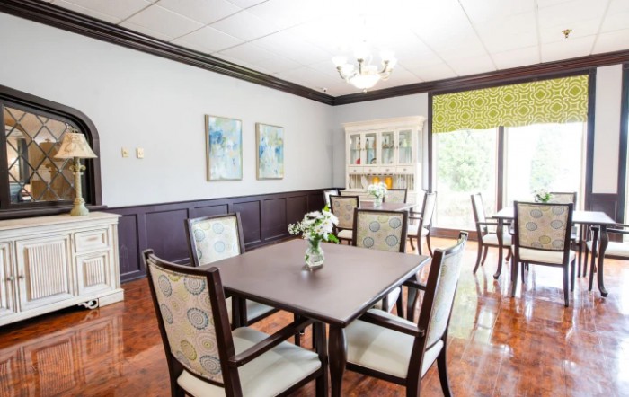 A well-lit dining room with a set of tables and chairs, featuring elegant artwork on the walls.