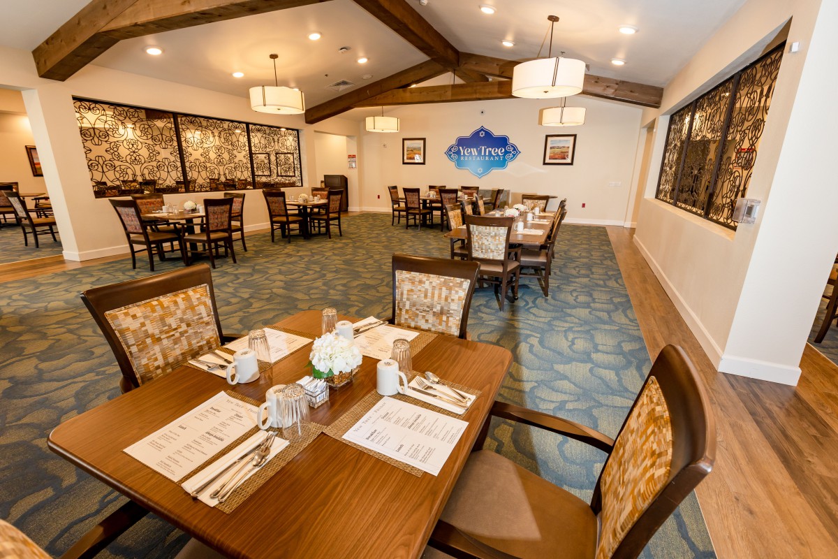 A well-lit dining room with neatly arranged tables and wooden furniture.