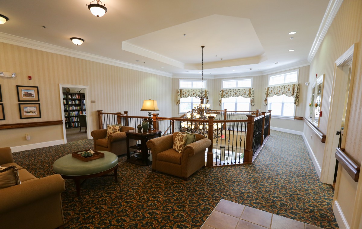 Spacious living area with comfortable seating, large windows, and a chandelier.