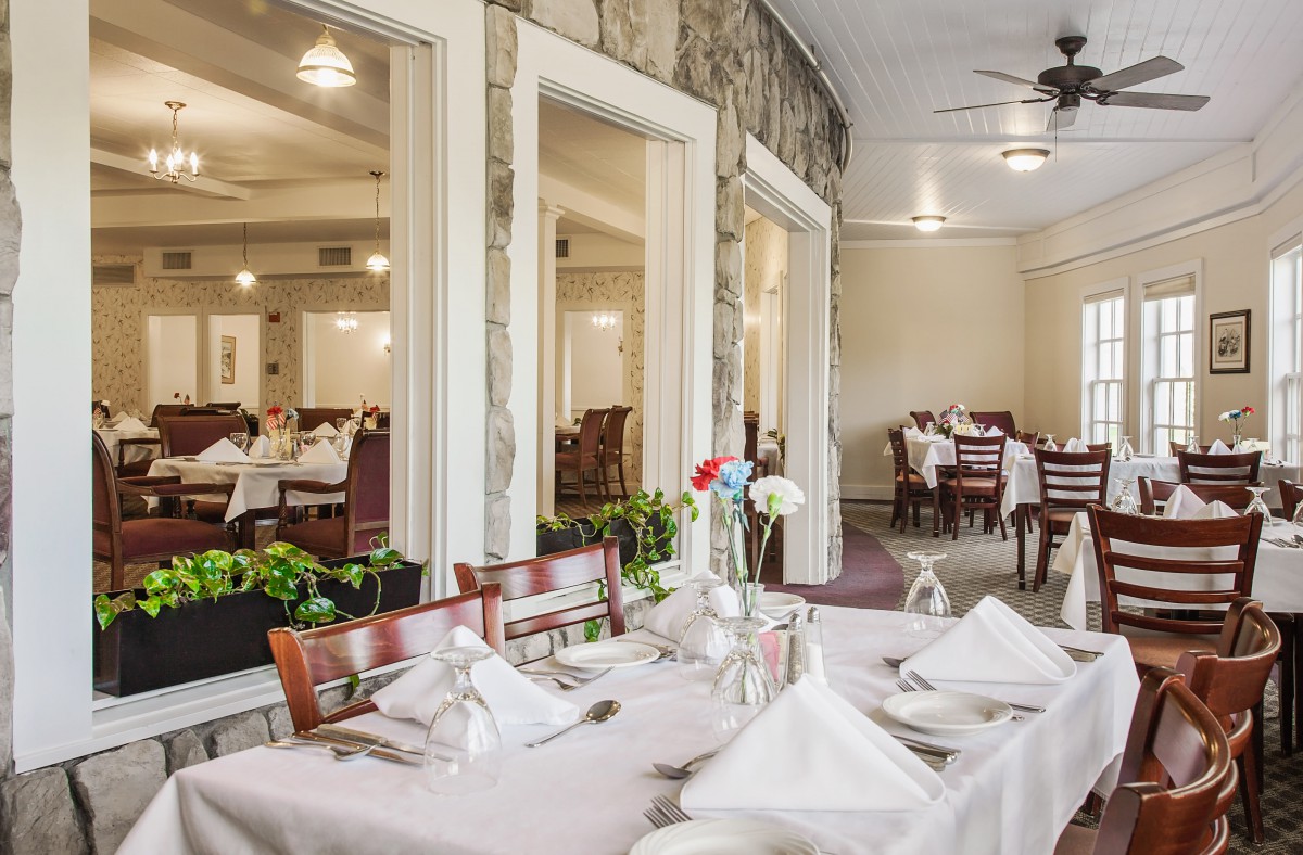 A well-set dining area in a restaurant, featuring neatly arranged tables and chairs with elegant table settings.