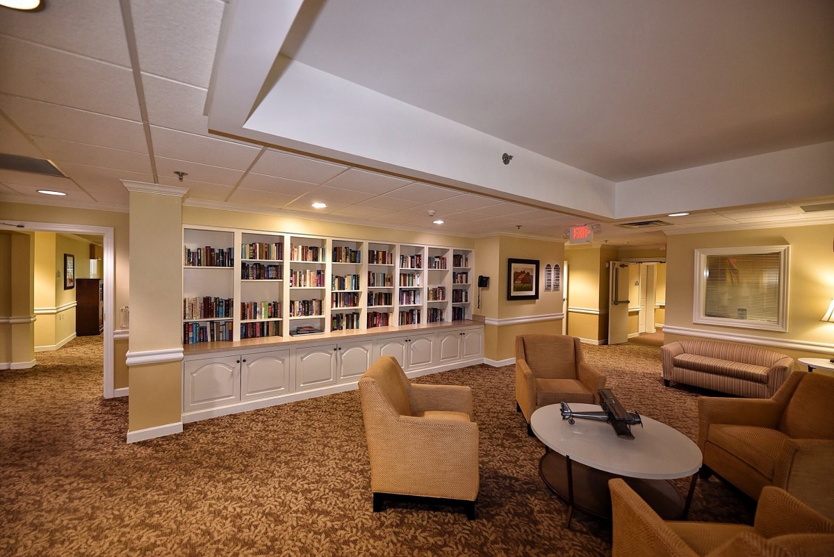 A cozy library seating area with bookshelves, comfortable chairs, and warm lighting.