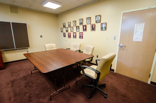 A meeting room featuring a conference table, chairs, and a wall adorned with framed photographs.