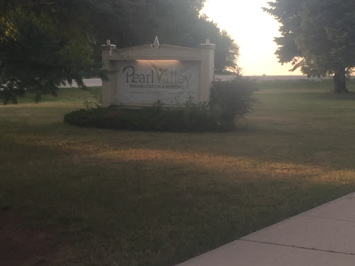 An inviting sign at dusk, surrounded by lush grass and trees.