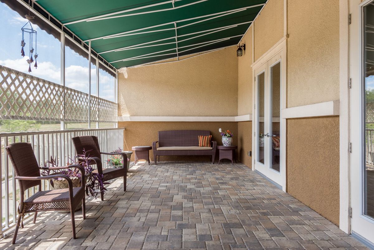 A cozy patio with comfortable seating arrangements under a green awning.