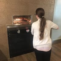 A woman placing something into a large oven.